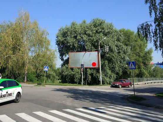 Фото рекламної площини за адресою вул.Прибузька, в районі мосту на "Епіцентр" та ТРЦ "Оазис". неподалік:  "Епіцентр", ТРЦ "Оазис", супермаркет "ТавріяВ" та "Сільпо", безліч дрібних магазинів та комерційних об'єктів (центр) [від центру, до Епіцентру]