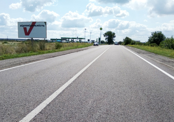 Фото рекламной плоскости по адресу выезд с г.Каменка-Бугская в направлении г.Львова, трасса Львов-Луцк (Н-17) + АЗК WOG + жовта вітрозахисна люмінесцентна рамка + висока конструкція